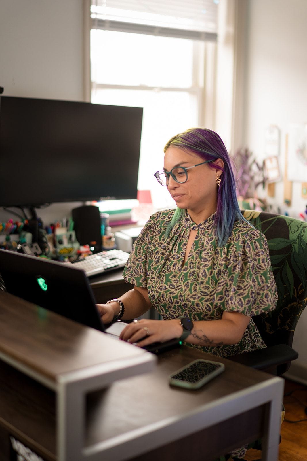 Joa Garcia, owner of Prism Consulting, sits at her desk working on her laptop.